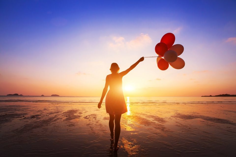 woman walking on the beach with balloons
