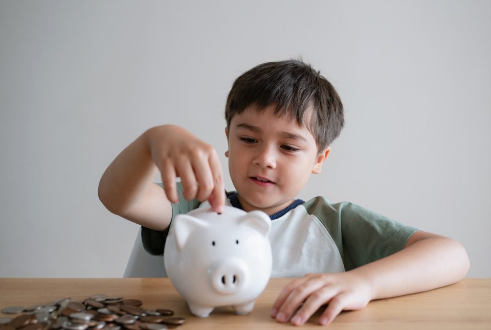 child putting coins into piggy bank
