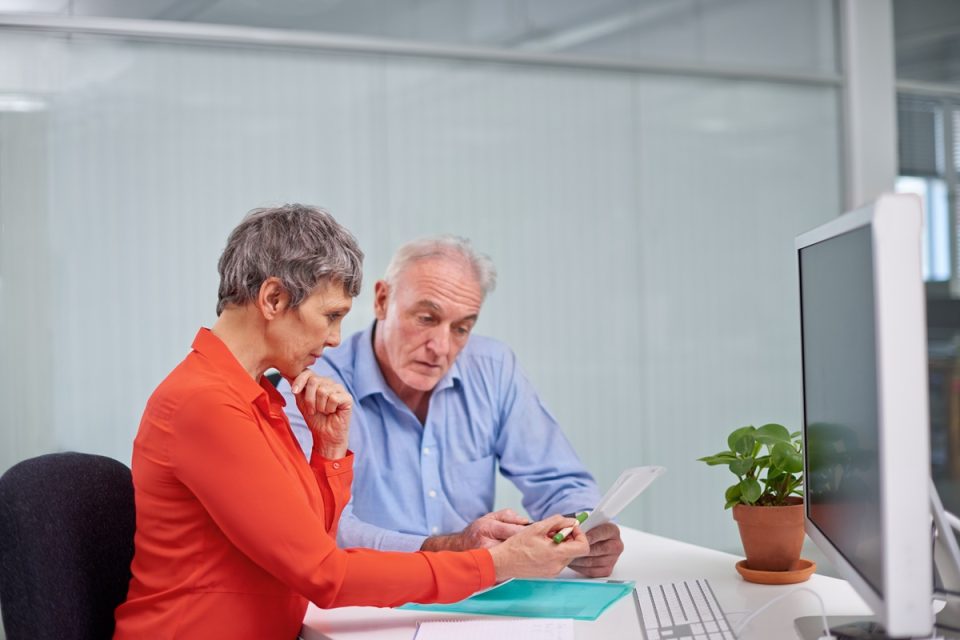 Man and woman in an office looking at paperwork together.