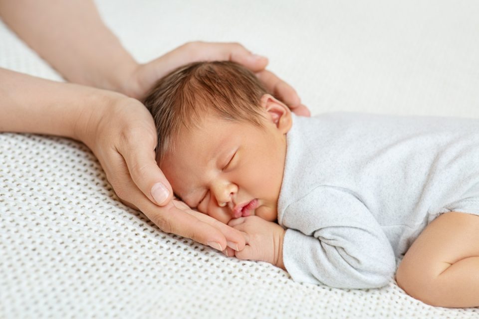 Mum cradling her newborn baby’s head.