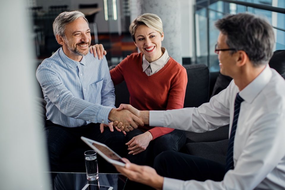 Couple shaking hands with an adviser
