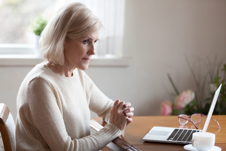 An anxious woman sitting at her laptop.