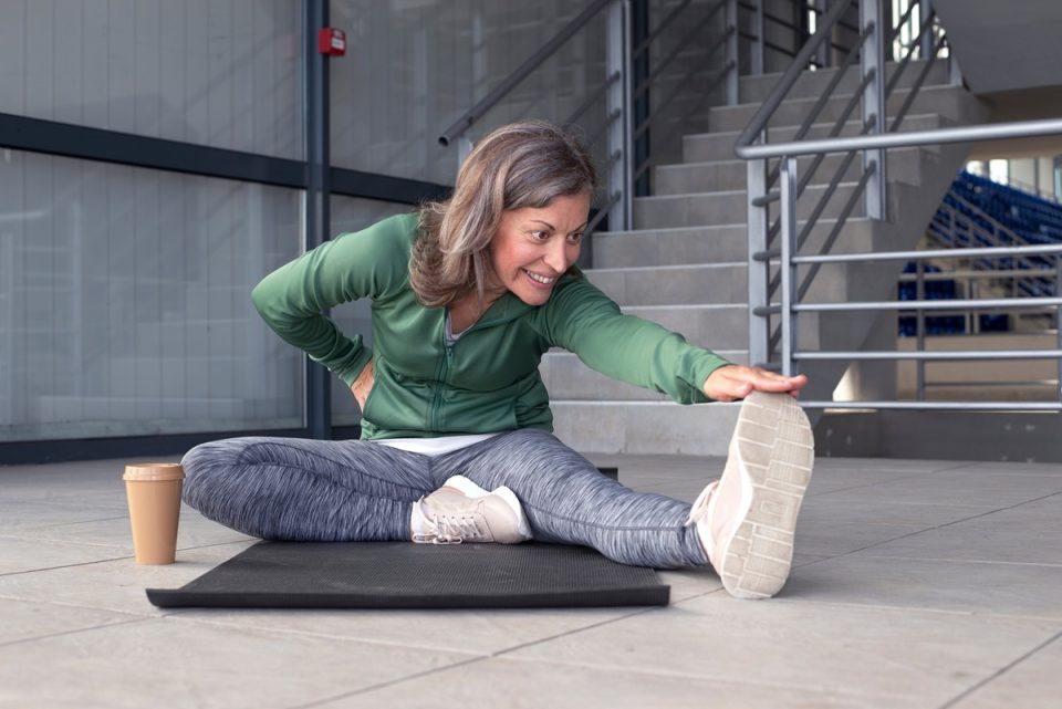 Woman touching her toes on a yoga mat.