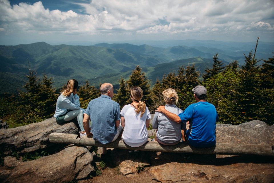 An intergenerational family sitting together looking out at a scenic view.
