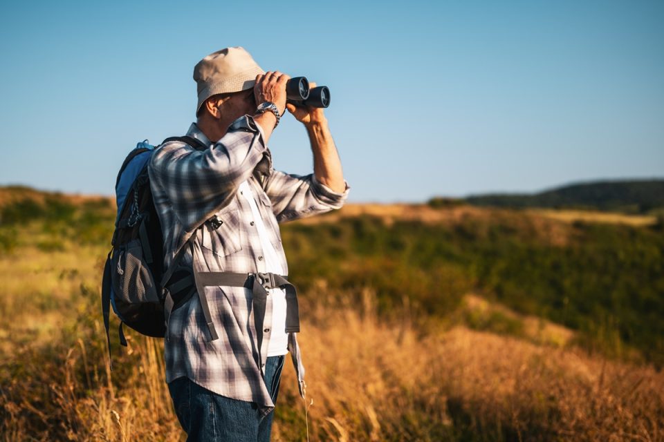 Older man holding binoculars.