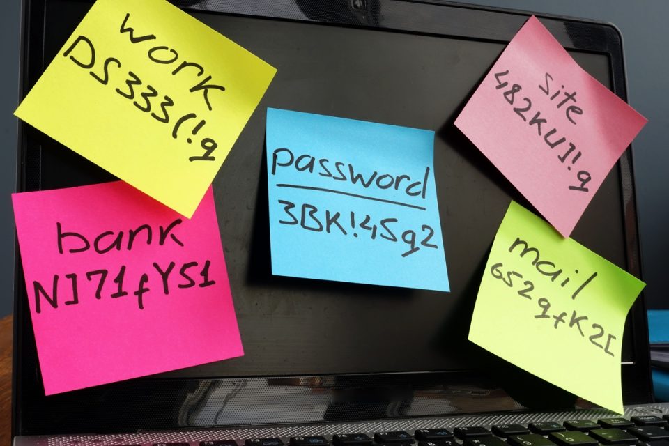 Passwords written on post-it notes stuck on a computer screen.