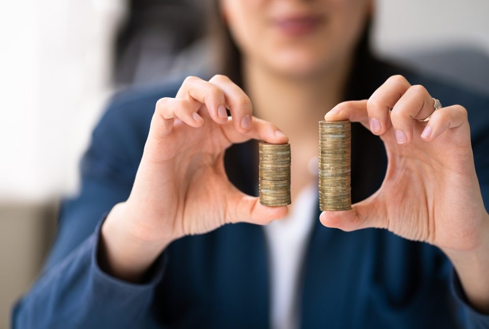 A woman holding two different-sized stacks of coins.